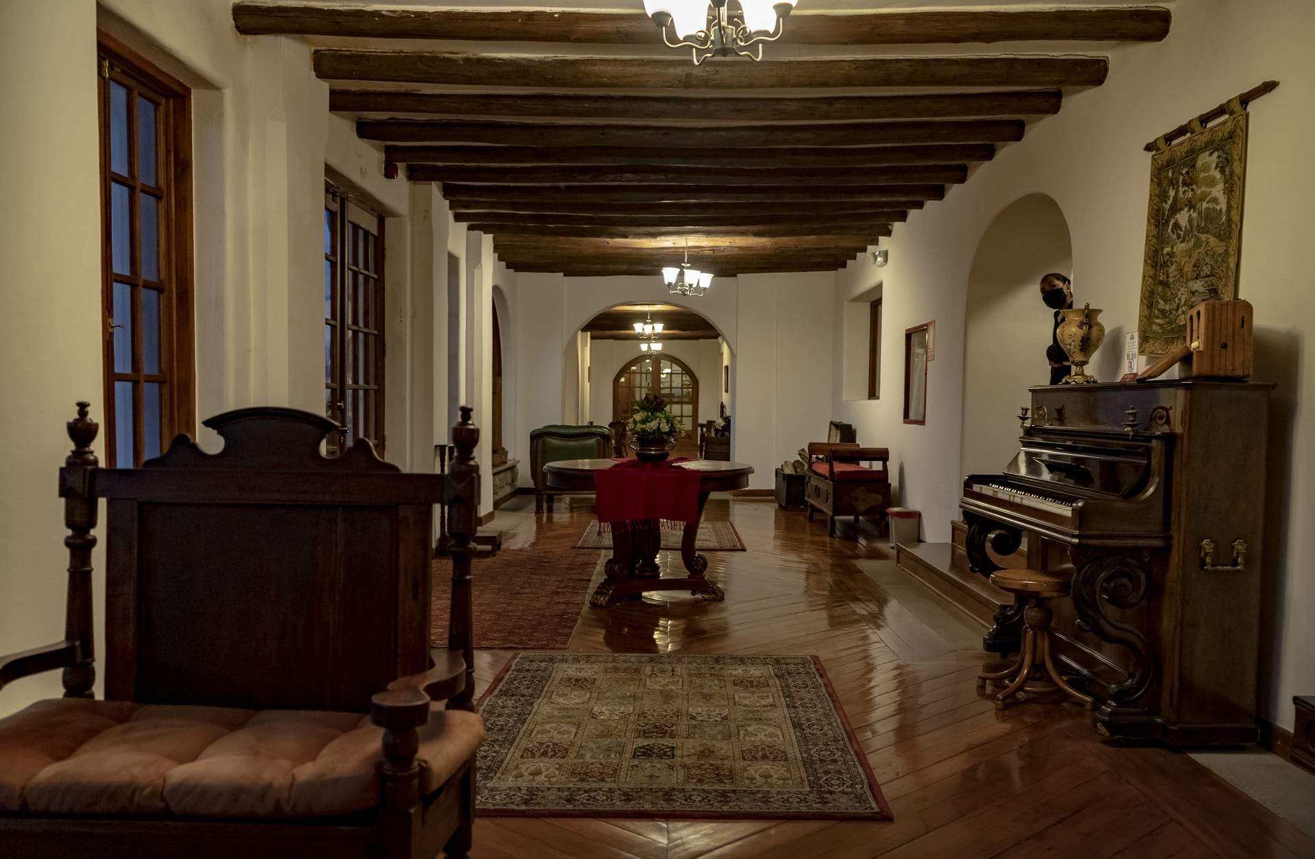 Vestíbulo de la Finca Hotel con vigas de madera, mobiliario antiguo y piano