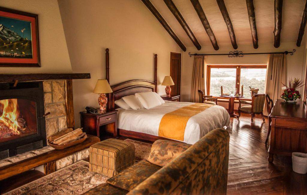 Habitación Cotopaxi con chimenea de piedra, cama y vigas de madera