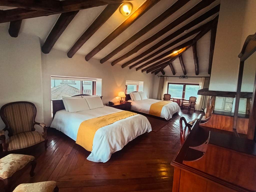 Dos camas bajo las vigas de madera de la habitación Cotopaxi