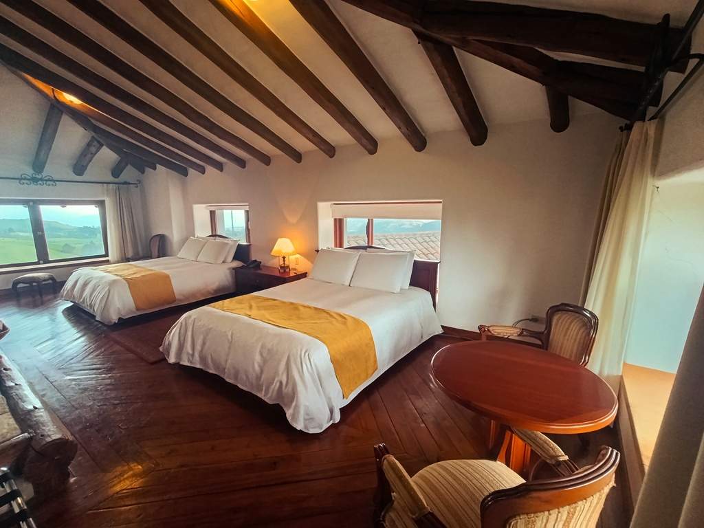 Dos camas y mesa junto a las ventanas de la habitación Cotopaxi