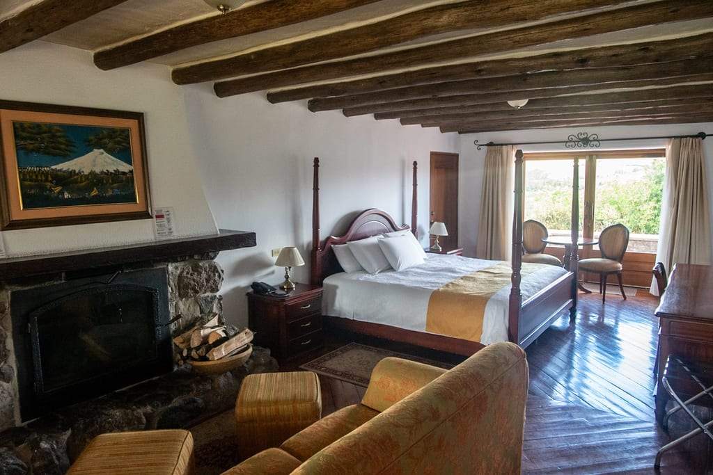 Habitación Sincholagua con chimenea, zona de descanso y puertas hacia la terraza